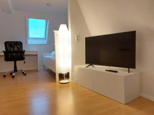 a living room with a flat screen tv and a chair at Rooftrop Apartments Ulm - komfortable neue Unterkunft im Herzen von Ulm in Ulm