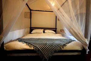 1 dormitorio con 1 cama con dosel en Temple Garden Seaside Cottages, en Palolem