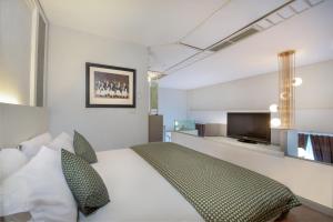 a bedroom with a bed and a flat screen tv at Lux Tychi Hotel in Malang