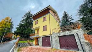 a yellow building with two garage doors on a street at Appartamento Livia - Affitti Brevi Italia in Bardonecchia