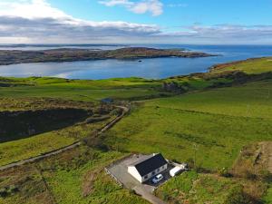 eine Luftansicht eines Hauses auf einem Feld mit See in der Unterkunft Cottage 171 - Clifden in Clifden