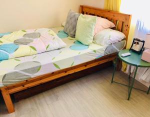 uma cama de madeira com almofadas e uma mesa num quarto em Amaia Steps Bicutan with Netflix and DisneyPlus - 1BR em Manila