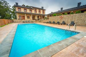 a swimming pool in front of a house at Apartamentos Navalin in Tapia de Casariego