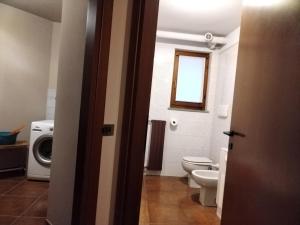 uma casa de banho com um WC e uma máquina de lavar roupa em Soggiorno Via del golf 41 em Carimate