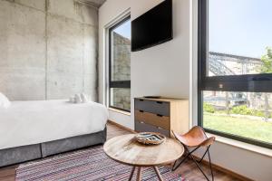 1 dormitorio con cama, mesa y TV en Bridge It - Suites & Views, en Vila Nova de Gaia