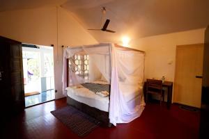 1 dormitorio con 1 cama con mosquitera en Temple Garden Seaside Cottages, en Palolem