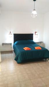 1 dormitorio con 1 cama verde y 2 almohadas de color naranja en Complejo La Carlota en San Juan
