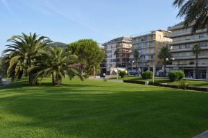 un parc avec des palmiers en face d'un bâtiment dans l'établissement Hotel Doria, à Chiavari