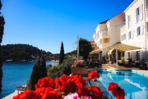 basen obok budynku z czerwonymi kwiatami w obiekcie Hotel Bozica Dubrovnik Islands w mieście Suđurađ