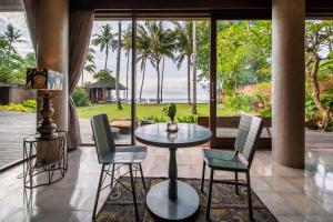 a patio with a table and chairs and a view of the ocean at Villa Manis Beachfront Candidasa in Candidasa