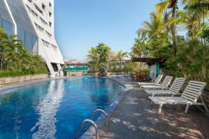 Lux Tychi Hotel في مالانغ: مسبح مع كراسي جلوس بجانب مبنى