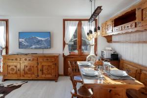 ein Esszimmer mit einem Tisch und einem TV in der Unterkunft HelloChalet - Foyer du Cervin 250m skiruns in Breuil-Cervinia