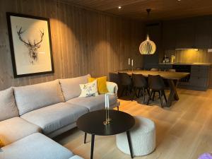 uma sala de estar com um sofá e uma mesa em Slåttastølen - ny og flott sentral leilighet! em Geilo