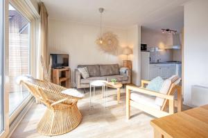 uma sala de estar com um sofá, uma mesa e cadeiras em De Leeuwerik em De Koog