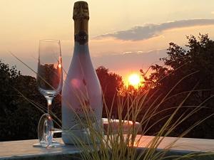 a bottle of wine and a glass on a table with the sunset at Luxus Spa Penthouse Sundowner in Göhren-Lebbin