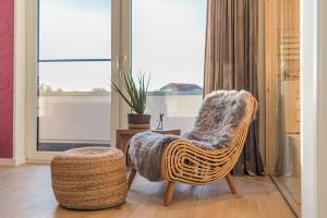 a rattan chair and stool in a room with a window at Luxus Spa Penthouse Sundowner in Göhren-Lebbin
