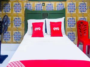 OYO 2518 Wilma Hotel Ii Premier في كوبانغ: غرفة نوم بسرير ومخدات حمراء