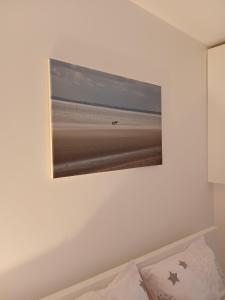 a picture of the beach on a wall above a bed at Le Blason du Poête in Mayet