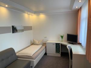 a room with a couch and a desk with a television at Pension Villa Transvaal in Ahlbeck