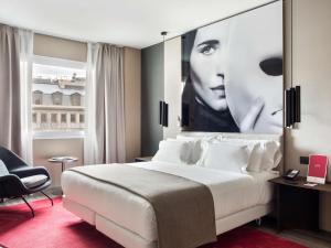 a hotel room with a bed and a large poster of a woman at NH Collection Madrid Suecia in Madrid