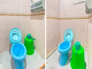 uma casa de banho com um WC azul e duas latas de lixo verdes em OYO 2518 Wilma Hotel Ii Premier em Kupang