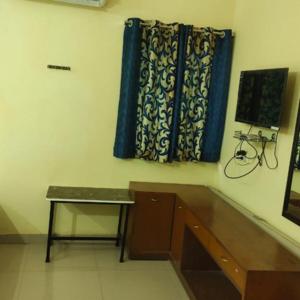 a room with a desk and a window with blue curtains at Geetha Residency in Kanchipuram
