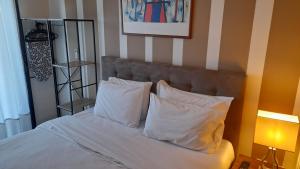 łóżko z białymi poduszkami i zdjęciem na ścianie w obiekcie Cabo Verde w mieście Agia Triada