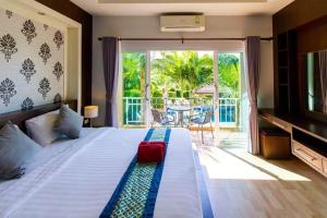 a bedroom with a bed and a balcony with a table at Phutara Lanta Resort - SHA Extra Plus Koh Lanta in Ko Lanta