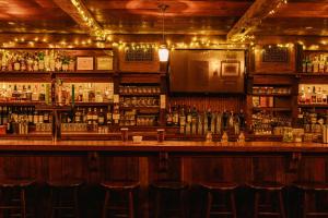 a bar with bar stools in a room with alcohol at The William powered by Sonder in New York