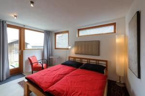 a bedroom with a red bed and a red chair at Loft am See in Hallstatt