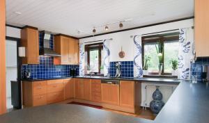 a kitchen with wooden cabinets and blue tiles at Private Room with No Windows in Shared House-4 in Umeå