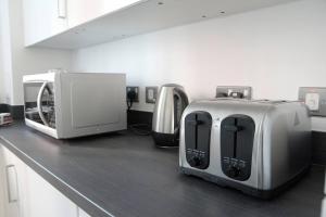 a counter top with a toaster and a microwave at Charming 3-Bed House in East central London in London