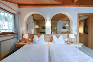 two beds in a room with two lamps and a mirror at Landhaus Grobert in Seeg