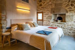 1 dormitorio con cama y pared de piedra en Hotel japonès Puigpinós, en Lladurs