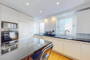 a kitchen with white cabinets and a black counter top at Stylish 2-bedroom flat in Bethnal Green in London