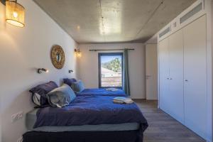 ein Schlafzimmer mit einem Bett mit blauer Decke und einem Fenster in der Unterkunft Appartement Dea in Sainte-Lucie de Porto-Vecchio