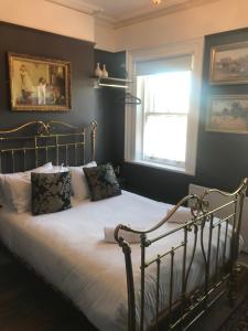 um quarto com uma cama com lençóis brancos e uma janela em The Warren Belfast em Belfast