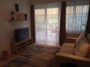 a living room with a couch and a flat screen tv at Csiribá Apartman in Cserkeszőlő