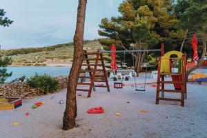 un parco giochi su una spiaggia accanto ad un albero di Boutique Camping Bunja a Supetar (San Pietro di Brazza)