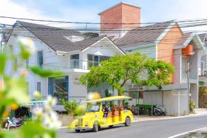 um pequeno carro amarelo dirigindo por uma rua em Vuon Xuan Hotel - STAY 24H em Da Lat