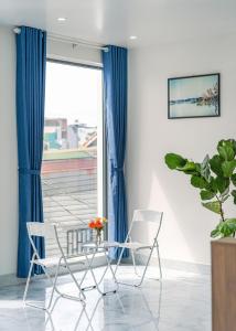 two chairs in front of a window with blue curtains at Vuon Xuan Hotel - STAY 24H in Da Lat