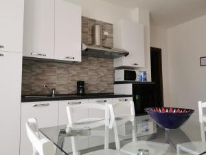 a kitchen with a glass table and white cabinets at Appartamenti Vanin in Cavallino-Treporti