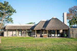 a house with a thatched roof and a yard at Longhill Lodge in Addo