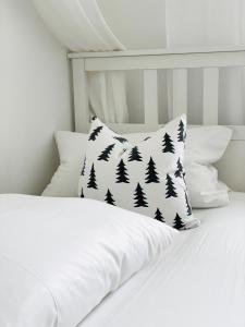Una cama blanca con una almohada con árboles. en Das Ruebezahl, en Reit im Winkl