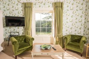 a living room with two green chairs and a window at Boyne House Slane in Slane