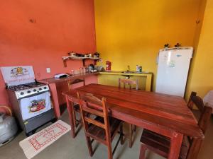 a kitchen with a table and a stove and a refrigerator at Vila Coqueiro - Moitas in Amontada