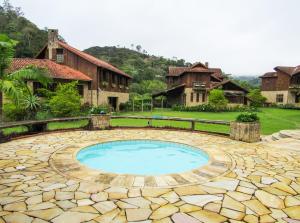 un patio de piedra con piscina frente a una casa en Casa de campo Azaleia c churrasqueira e lazer - RJ, en Teresópolis