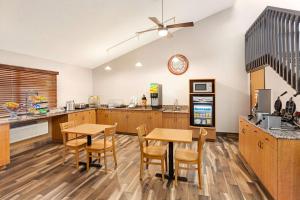 a kitchen with wooden cabinets and tables and a refrigerator at AmericInn by Wyndham Sauk Centre in Sauk Centre