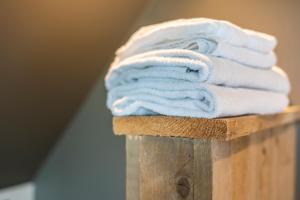 una pila de toallas blancas en un poste de madera en M-otel E40, en Wetteren