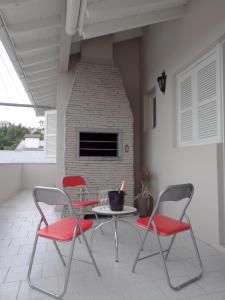 um pátio com 3 cadeiras, uma mesa e uma lareira de tijolos em Casa Bem Vino em Bento Gonçalves
